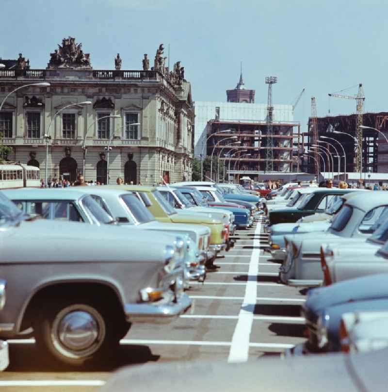 Blick über die parkenden Autos auf dem Mittelstreifen Unter den Linden in Berlin-Mitte zum Zeughaus, dem noch im Bau befindlichen Palast der Republik (PdR) und der Spitze des Roten Rathauses.