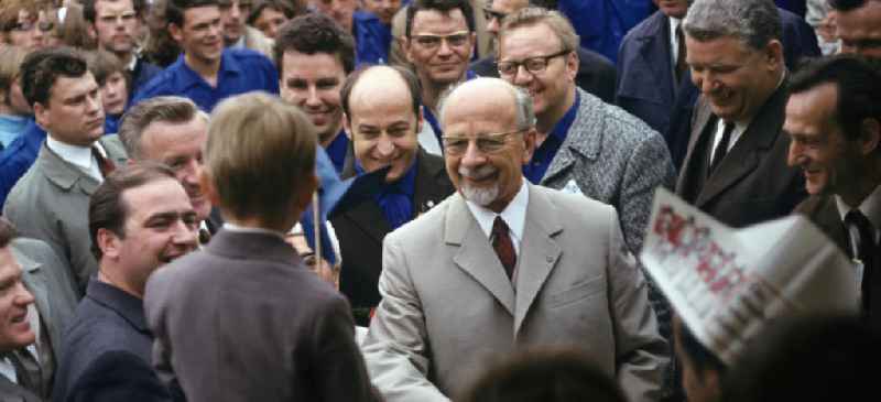 Der Erste Sekretär der SED und Vorsitzende des Staatsrates der DDR, Walter Ulbricht, scherzt in einer Menschenmenge mit einem Jungen.