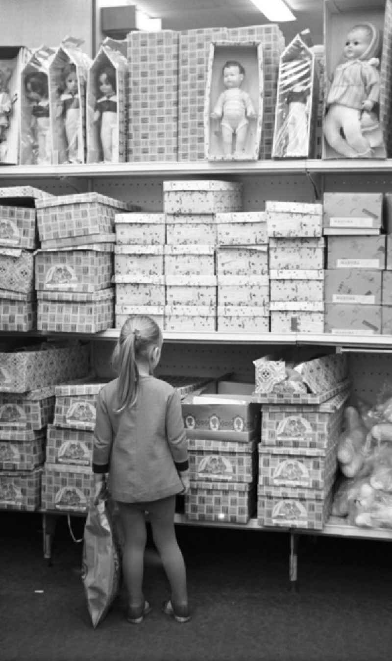 Ob Mutti die mir kauft?, denkt dieses Mädchen vielleicht, das in der Spielwarenabteilung im Centrum Warenhaus am Alex in Berlin vor einem Regal mit Puppen steht und in einen geöffneten Karton schaut.