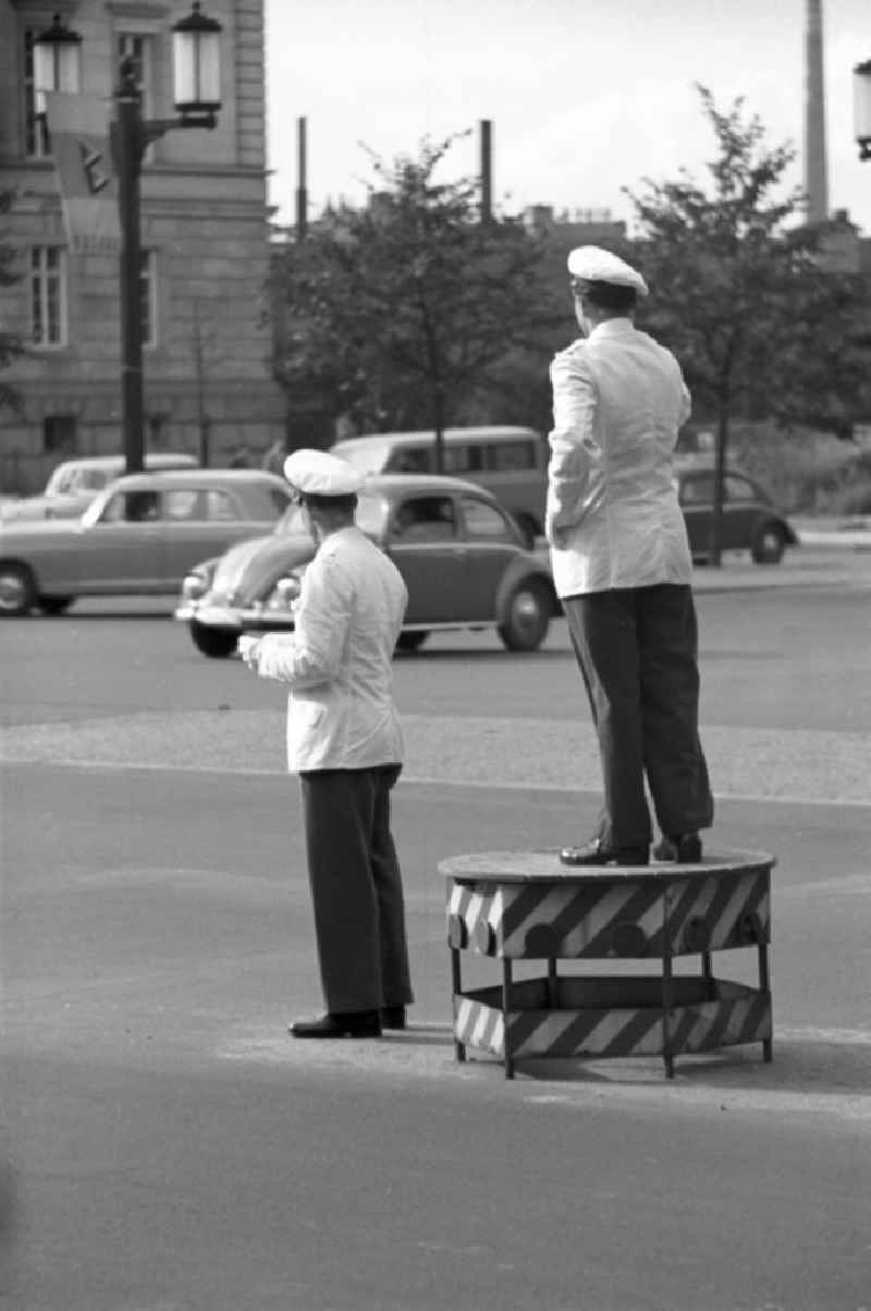 Verkehrspolizisten regeln auf der Straße des 17. Juni in Westberlin den Verkehr. Im Hintergrund Werbung für die Interbau, die Internationale Bauausstellung 1957. In den 5
