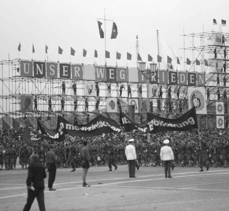 Zu Pfingsten 1964, vom 16.-18. Mai, findet in Berlin das letzte 'Deutschlandtreffen der Jugend für Frieden und Völkerfreundschaft' statt, hier Aufmarsch vor der Ehrentribüne auf dem Marx-Engels-Platz (heute Schloßplatz). An dem Gerüst im Hintergrund hängen Motive ost- und westdeutscher Städte und die Losung 'Unser Weg - Frieden'. Ziel der ersten Veranstaltung im Mai 1950 war, die kommunistische Jugend in Ost und West mobil zu machen und der damals in der BRD noch zugelassenen FDJ neue Anhänger zuzuführen. 1951 wurde das Verbot gegen die FDJ in der BRD ausgesprochen. Nach 1964 entsprach eine gesamtdeutsche kommunistische Politik nicht mehr den Zielen der DDR-Regierung. In den 70er und 8