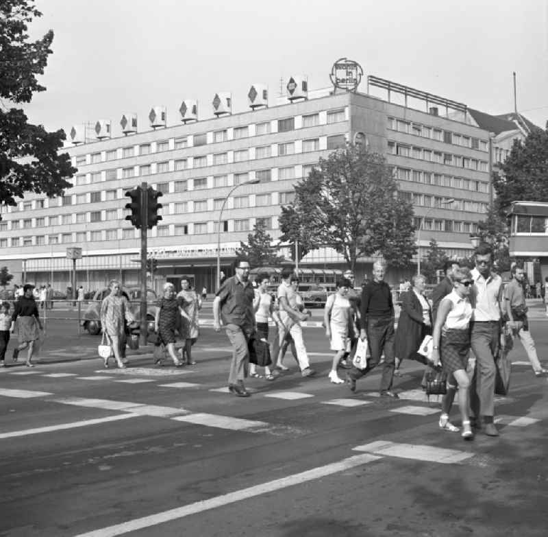 Passanten überqueren Ost-Berlins beliebteste Flaniermeile Unter den Linden, im Hintergrund das Hotel Unter den Linden. Das Mitte der 60er Jahre errichtete Hotel an der Friedrichstraße / Ecke Unter den Linden war eines der ersten Neubauten der Interhotel-Kette der DDR. Das Gebäude wurde 20
