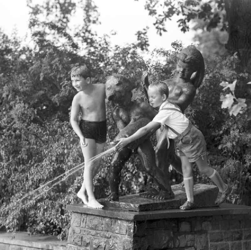 Kinder spielen an einer Wasserfontäne einer Skulptur im Tierpark Berlin-Friedrichsfelde.