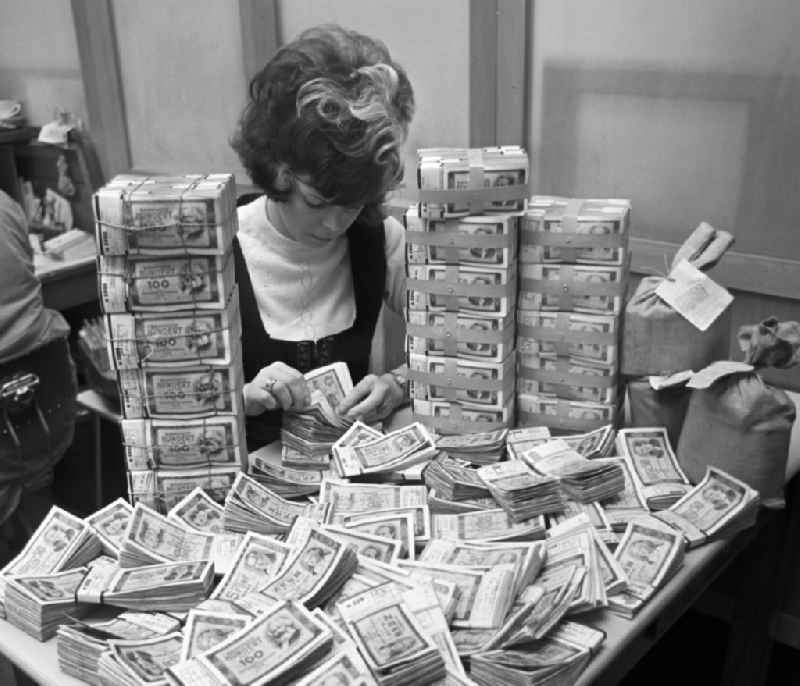 Various mark banknotes in stacks on the table of a bank employee as legal tender and currency put into circulation by the state bank in the Mitte district of Berlin, East Berlin in the territory of the former GDR, German Democratic Republic