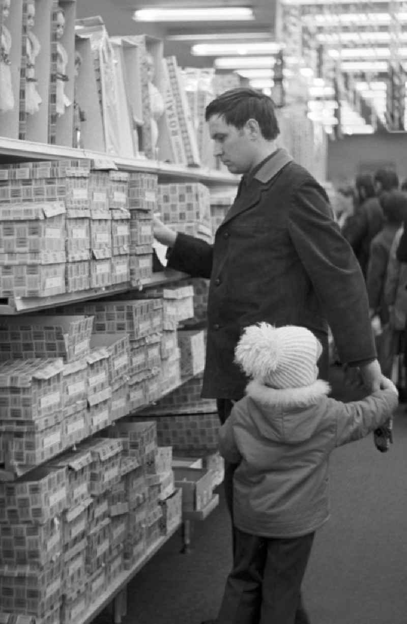 Ein Mann steht mit seinem Kind vor einem Regal mit Anziehpuppen in der Spielzeugabteilung im Centrum Warenhaus in Berlin.