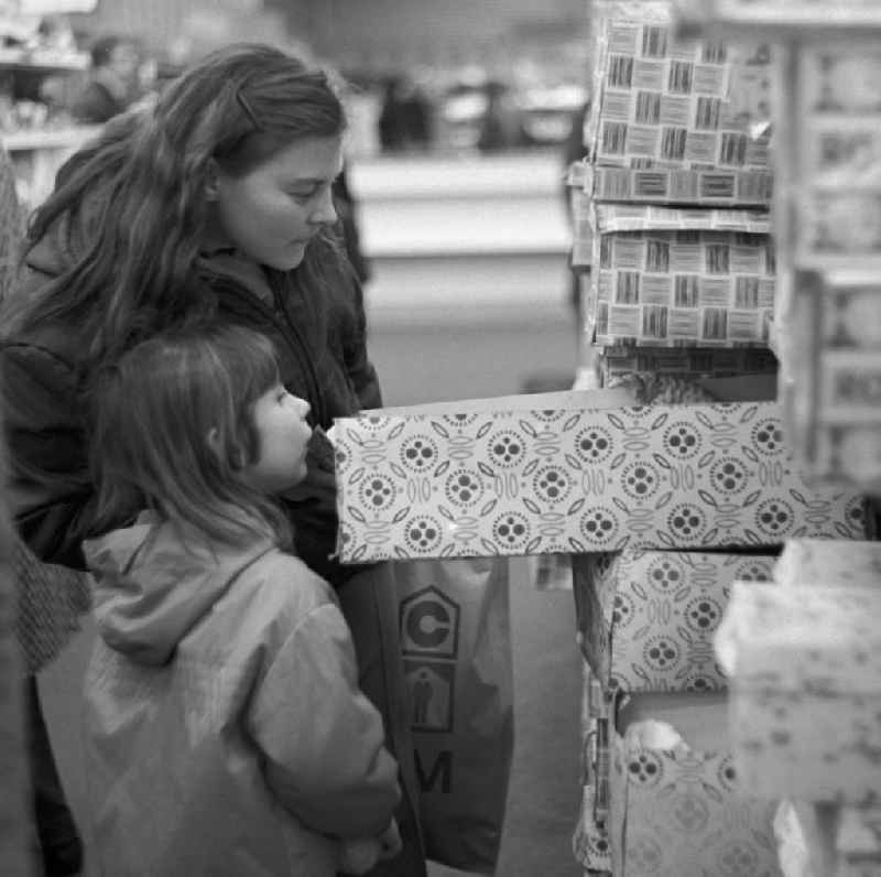 Ein Mädchen blickt mit ihrer Mutti neugierig in einen Karton mit einer Anziehpuppe in der Spielzeugabteilung im Centrum Warenhaus in Berlin.