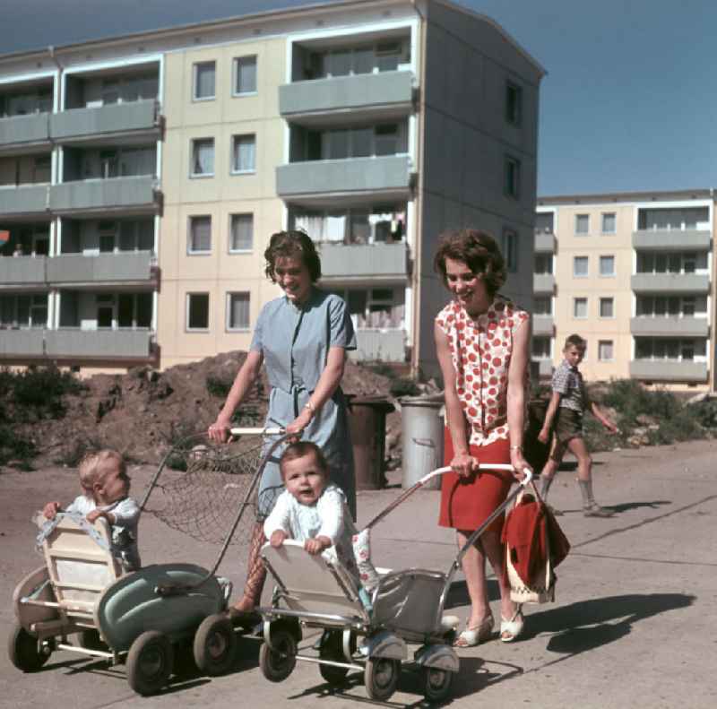 Drei Muttis gehen mit ihren Kinderwagen und Babys in einem Neubauviertel in Berlin spazieren.