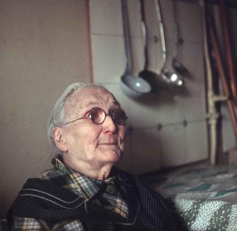 Eine alte Frau sitzt in einer Küche in Berlin.