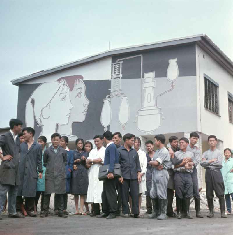 Vietnamesische Praktikanten stehen vor den Gebäuden des VEB Berlin-Chemie, wo sie ihre Ausbildung absolvieren. Vietnamesen bildeten in der DDR die größte Gruppe an Arbeitskräfte aus den sozialistischen Bruderländern.