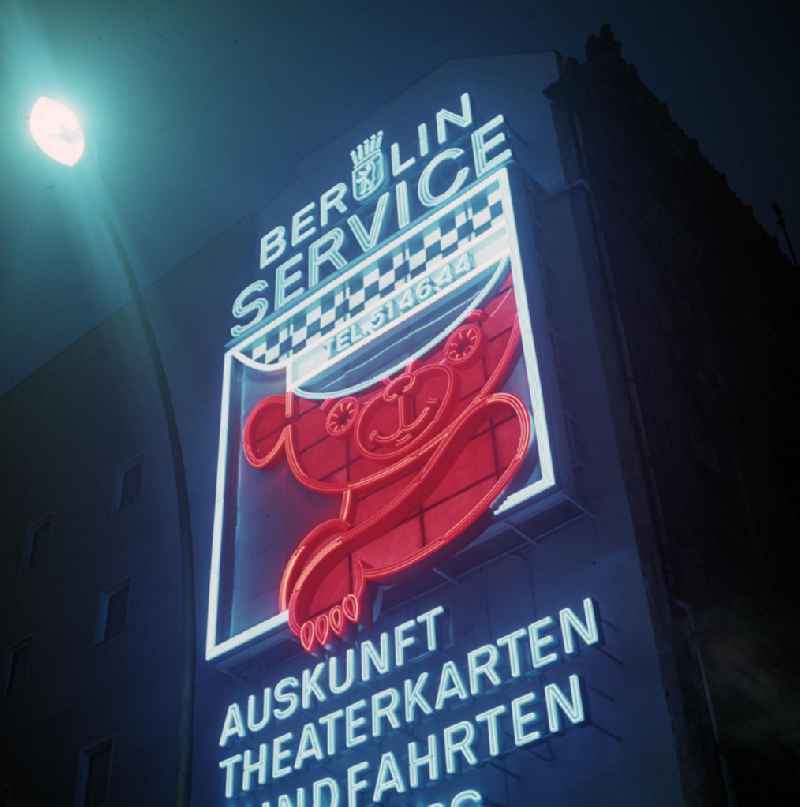 Nachtaufnahme: Eine Leuchtreklame wirbt Unter den Linden mit einem Berliner Bären als Symbol für den 'Berlin Service' der Hauptstadt der DDR, der Dienstleistungen in den Bereichen Auskunft, Theaterkarten, Rundfahrten und Souvenirs anbietet.