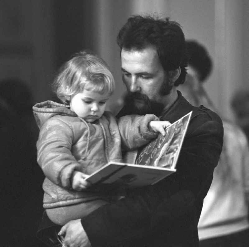 Ein Kind betrachtet auf dem Arm des Vaters ein Bilderbuch auf dem Schriftstellerbasar in Berlin.