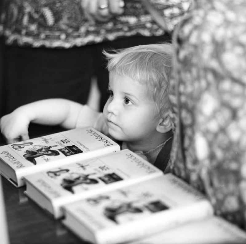 Ein Kind schaut über den Büchertisch bei der Autogrammstunde des Schriftstellers Rolf Gerlach in der Karl-Marx-Buchhandlung in Berlin.
