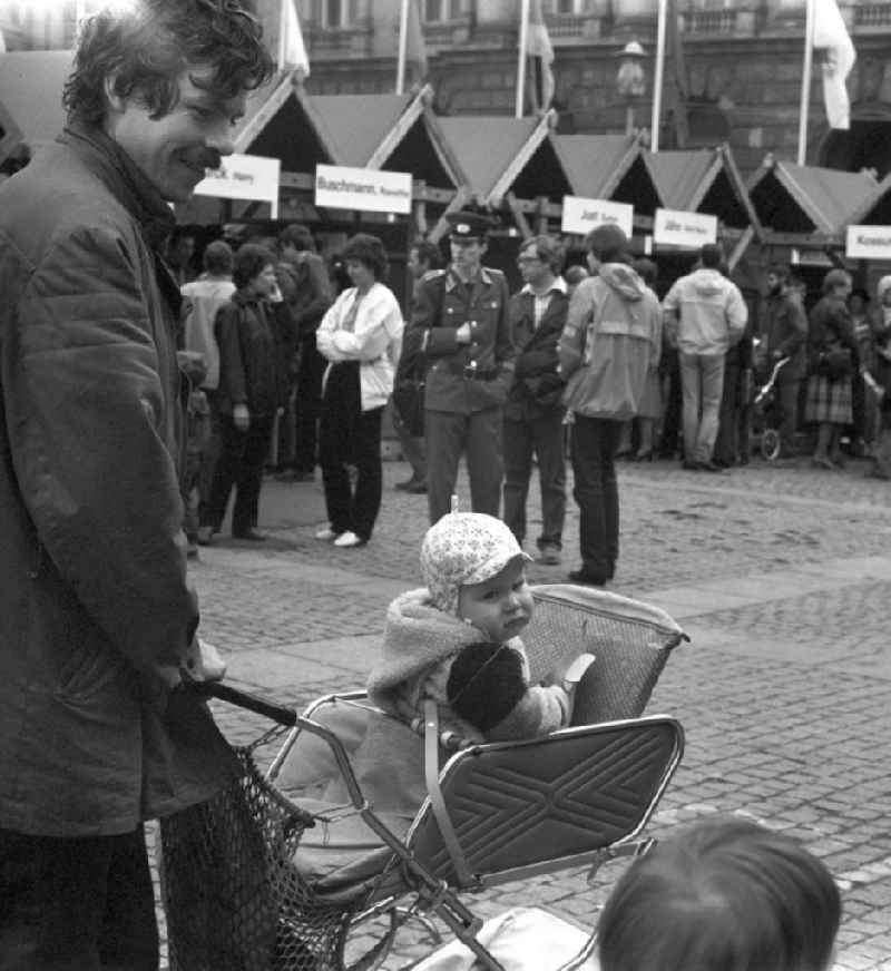 Vater mit Kindern auf dem Schriftstellerbasar auf dem Bebelplatz in Berlin. Bekannte DDR-Schriftsteller und -Schriftstellerinnen hatten sich auf dem Büchermarkt zusammengefunden, um ihre Bücher vorzustellen und Autogramme zu verteilen.