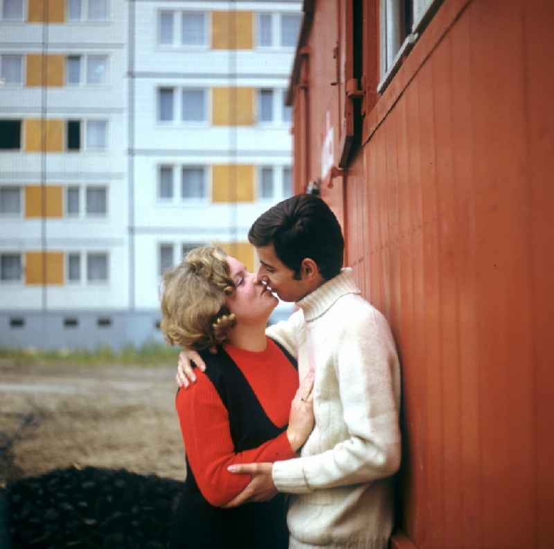 A young couple kissing each other on a Mobile Home in a newly constructed block district