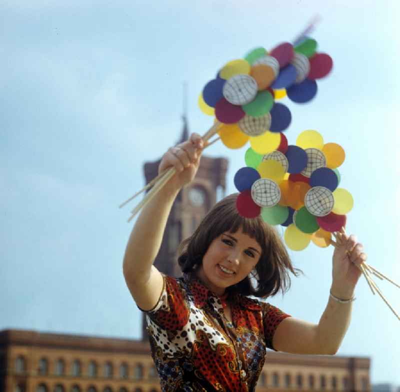 Eine junge Frau hält Windmühlen mit dem Logo der X. Weltfestspiele 1973 in Berlin in den Händen. A young woman holding windmills with the logo of X. World Festival 1973 in Berlin in the hands.