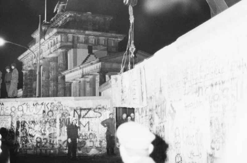 Demontage von Betonsegmenten der Berliner Mauer zur Öffnung eines Grenzüberganges am Brandenburger Tor in Berlin- Mitte. Durch Baupioniere und Soldaten der Grenztruppen der DDR wurden L- Profile aus der ehmaligen Befestigungsanlage der DDR Staatsgrenze zu Westberlin entfernt.// Dismantling of concrete segments of the Berlin Wall to the opening of a border crossing at the Brandenburg Gate in Berlin-Mitte. By Baupioniere and soldiers of the Border Troops of the GDR L-profiles were removed from the ramparts of the GDR border to West Berlin.