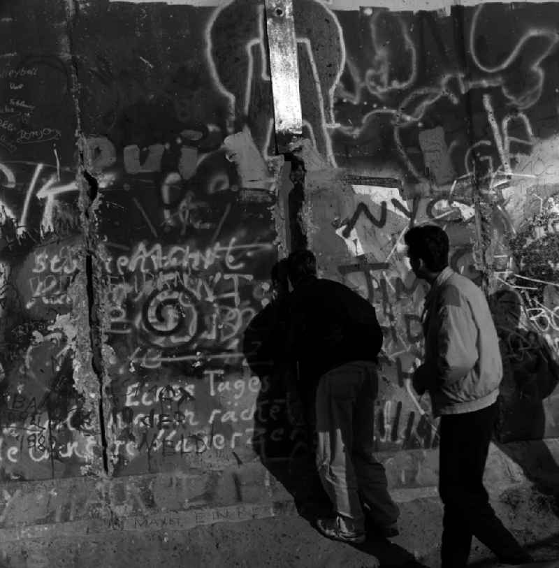 Curious tourists and Berlin look through a hole in the Berlin wall on the other side of Berlin