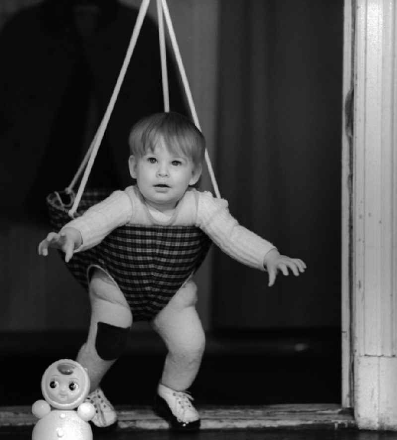 Toddler in a baby swing mounted in a door frame in Berlin
