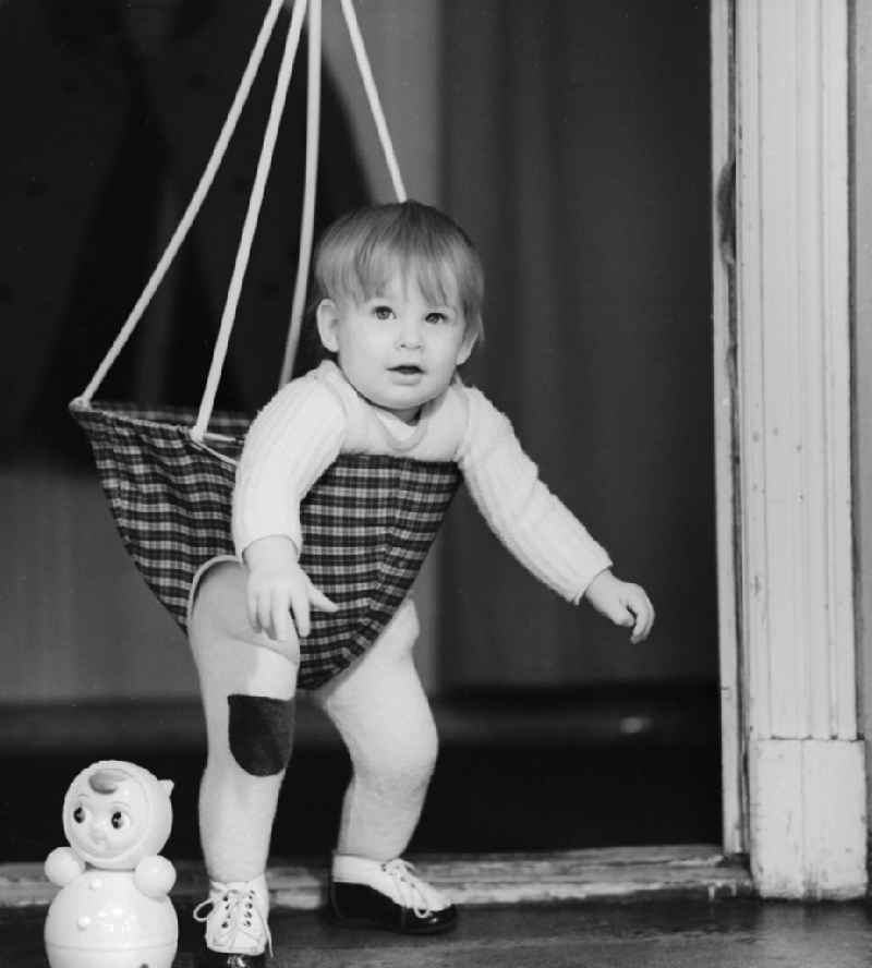 Toddler in a baby swing mounted in a door frame in Berlin