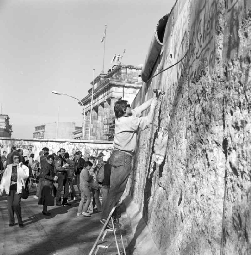 Wallpeckers and souvenir collectors at the Berlin Wall at the Brandenburg Gate in Berlin. As wallpeckers people were popularly known, the edited the Berlin Wall after the Wall fell in 1989 and crushed