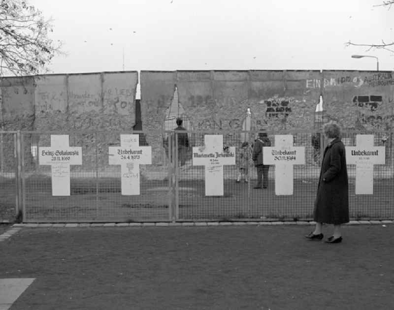 White crosses on a fence in front of the Berlin Wall in Berlin. Each white cross represents a person who died while trying to escape from East Germany