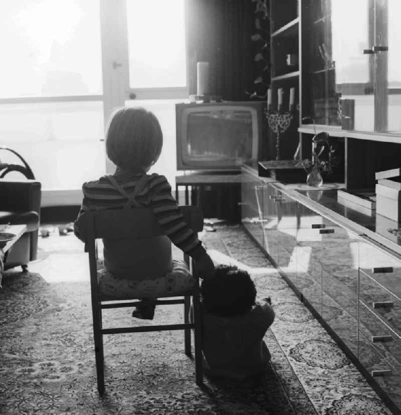 Small child sitting in front of the TV in the living room in Berlin