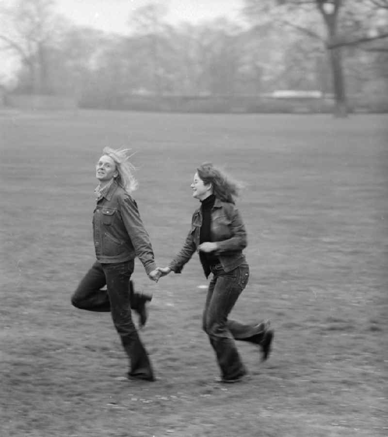 Young couple running through a meadow in Berlin