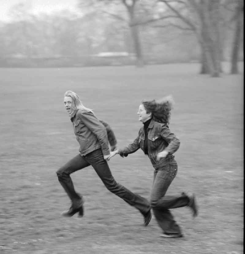 Young couple running through a meadow in Berlin