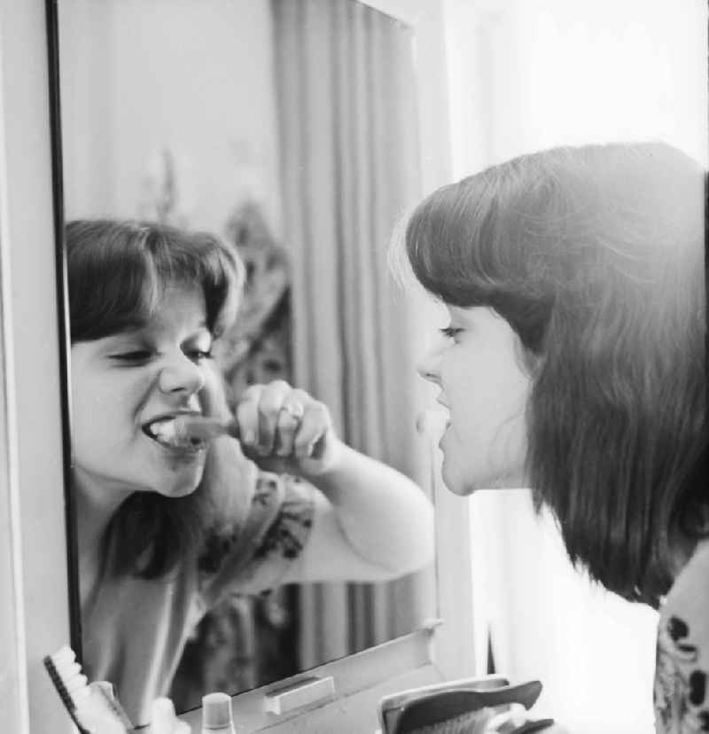 Young woman brushing teeth in front of the mirror in Berlin