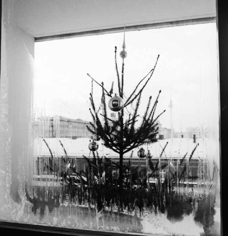 A decorated Christmas tree in front of a window with ice flowers in Berlin