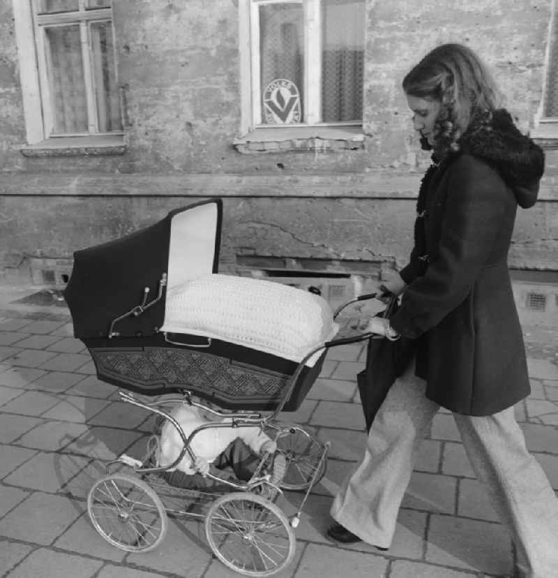 Young mother with a pram on a walk in Berlin. Above is the baby in the basket and sits below the larger sibling