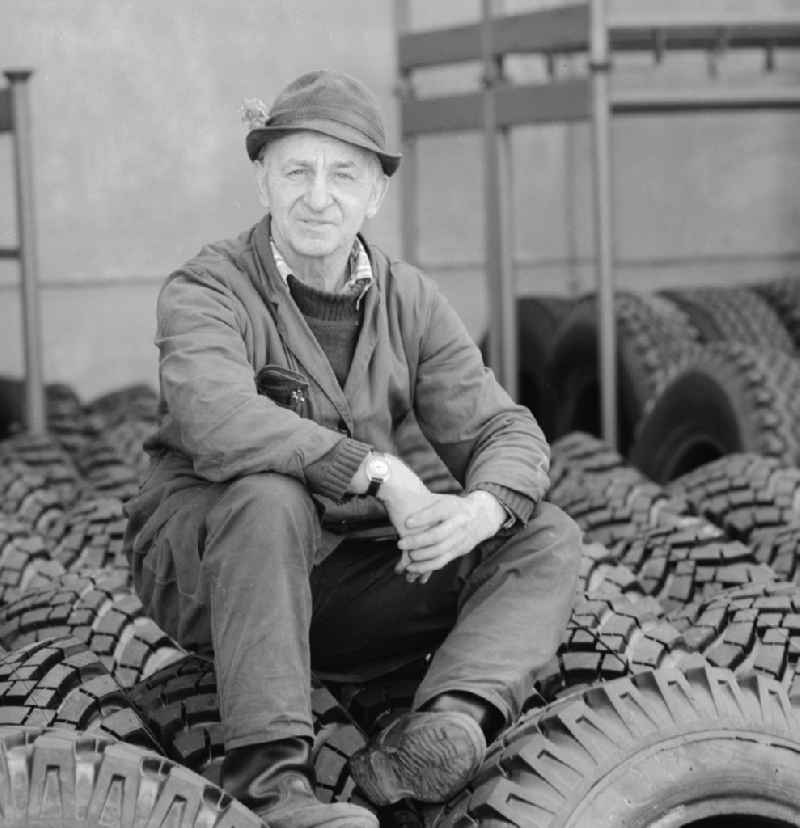 An elderly man with hat sitting on tires in a spare parts store in Berlin