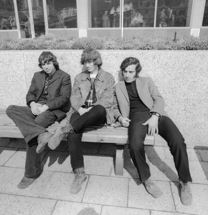 Three teenagers on a wooden park bench in Berlin
