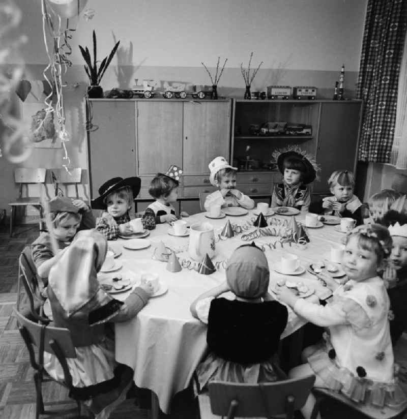 Carnival in kindergarten in Berlin. The clad children sit at the table decorated Vesper