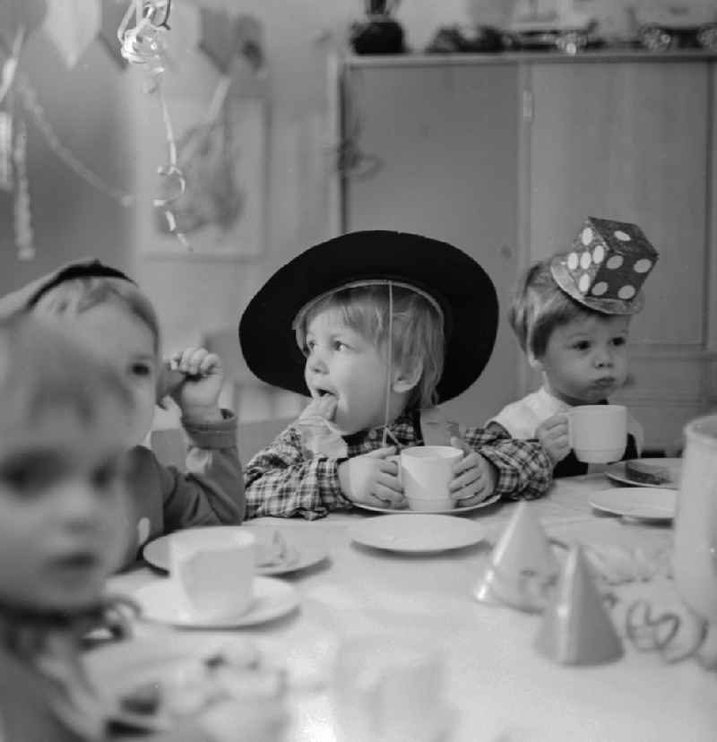 Carnival in kindergarten in Berlin. The clad children sit at the table decorated Vesper