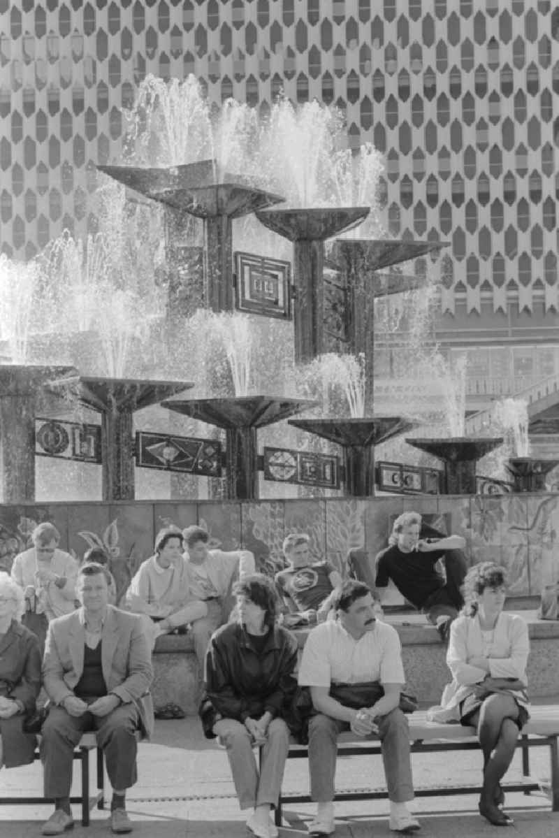 Pedestrians dwelling at the fountain at the Alexanderplatz in Berlin in Germany