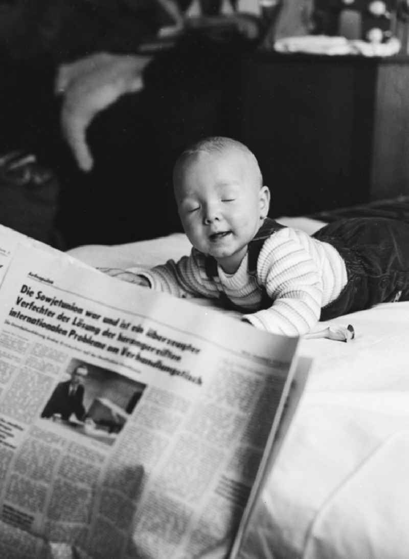 A toddler on a playmat in Berlin, the former capital of the GDR, the German Democratic Republic. In the foreground, a daily newspaper
