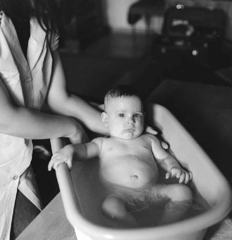 A mother bathes her baby in a plastic tub in Berlin, the former capital of the GDR, the German Democratic Republic