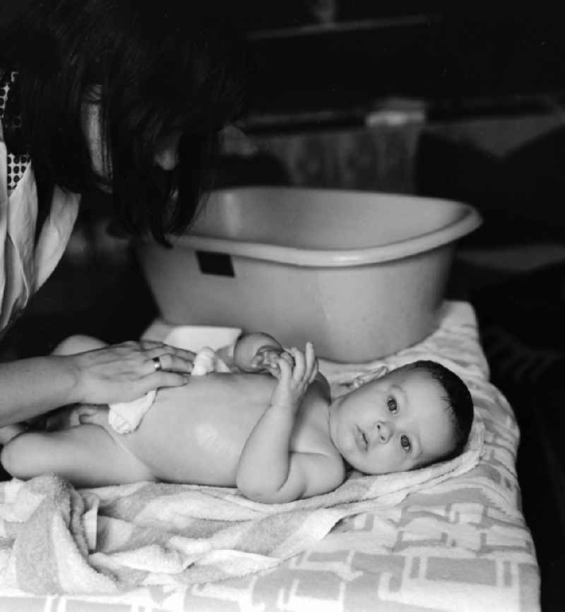 A mother bathes her baby in a plastic tub in Berlin, the former capital of the GDR, the German Democratic Republic