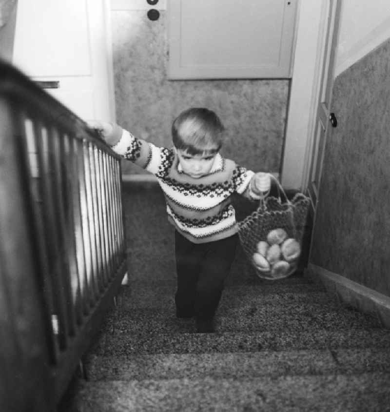 Child carrying a shopping bag with bread rolls in a stairwell in Berlin, the former capital of the GDR, the German Democratic Republic