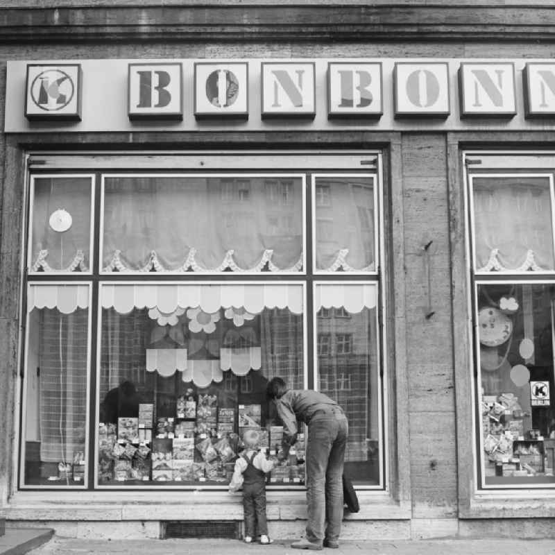 A father is KONSUM -lding his child in front of a KONSUM - grocers in the district Friedrichshain in Berlin, the former capital of the GDR, the German Democratic Republic