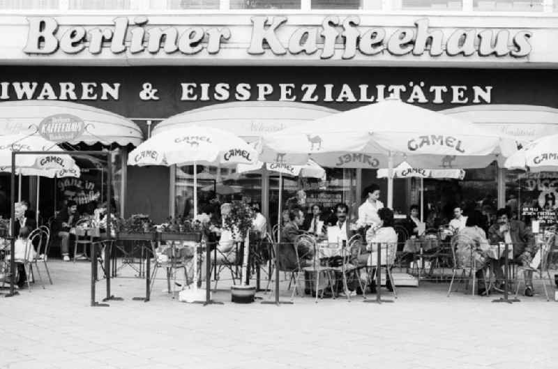 Outdoor terrace by the Berlin cafe in Berlin, the former capital of the GDR, the German Democratic Republic. The Berliner coffee house was a restaurant, cafe and ice cream parlor. On the outdoor terrace with parasols advertising