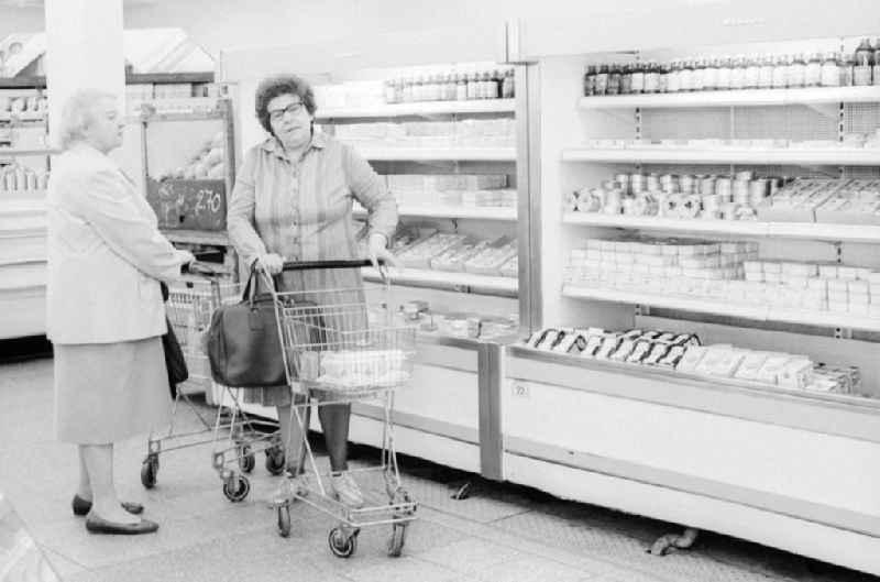 2 elderly ladies chatting in front of the refrigerated shelves in a department store in Berlin, the former capital of the GDR, the German Democratic Republic. The shelves are filled partly with Ostprodukten as well with Western products