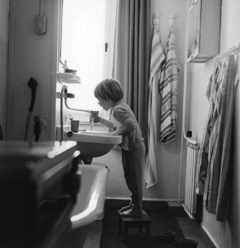 Child while brushing your teeth in a newly built bathroom with central heating in Berlin, the former capital of the GDR, the German Democratic Republic