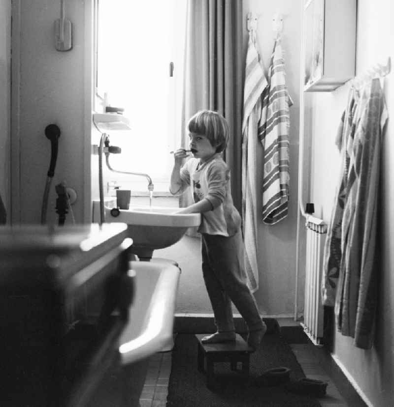 Child while brushing your teeth in a newly built bathroom with central heating in Berlin, the former capital of the GDR, the German Democratic Republic