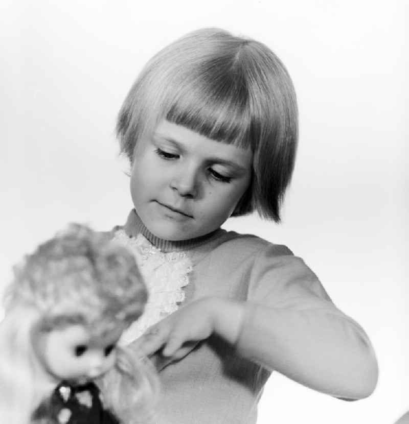 A small child playing with a doll in Berlin, the former capital of the GDR, German Democratic Republic