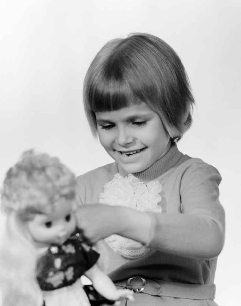 A small child playing with a doll in Berlin, the former capital of the GDR, German Democratic Republic