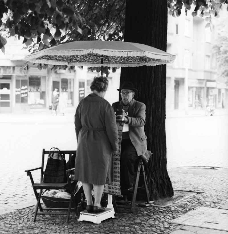 With hat and suit dressed elderly gentleman in weighing of road passersby on the Schoenhauser Allee in Berlin, the former capital of the GDR, German Democratic Republic. For a Woman can be or a passing Obolus 1