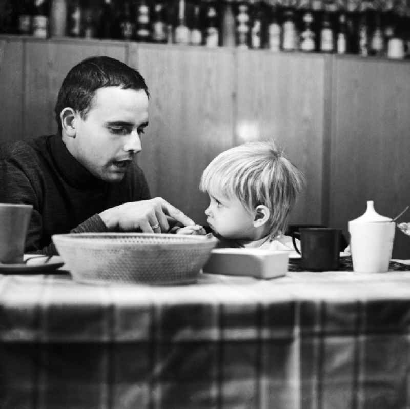 A father sitting with his child at the breakfast table in Berlin, the former capital of the GDR, German Democratic Republic