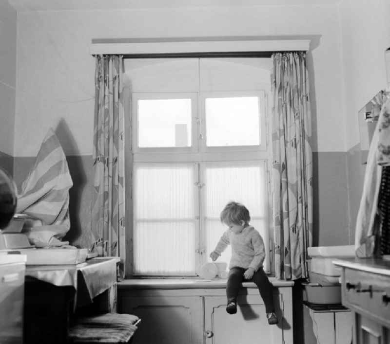 A child sitting on a windowsill with his toys in Berlin, the former capital of the GDR, German Democratic Republic